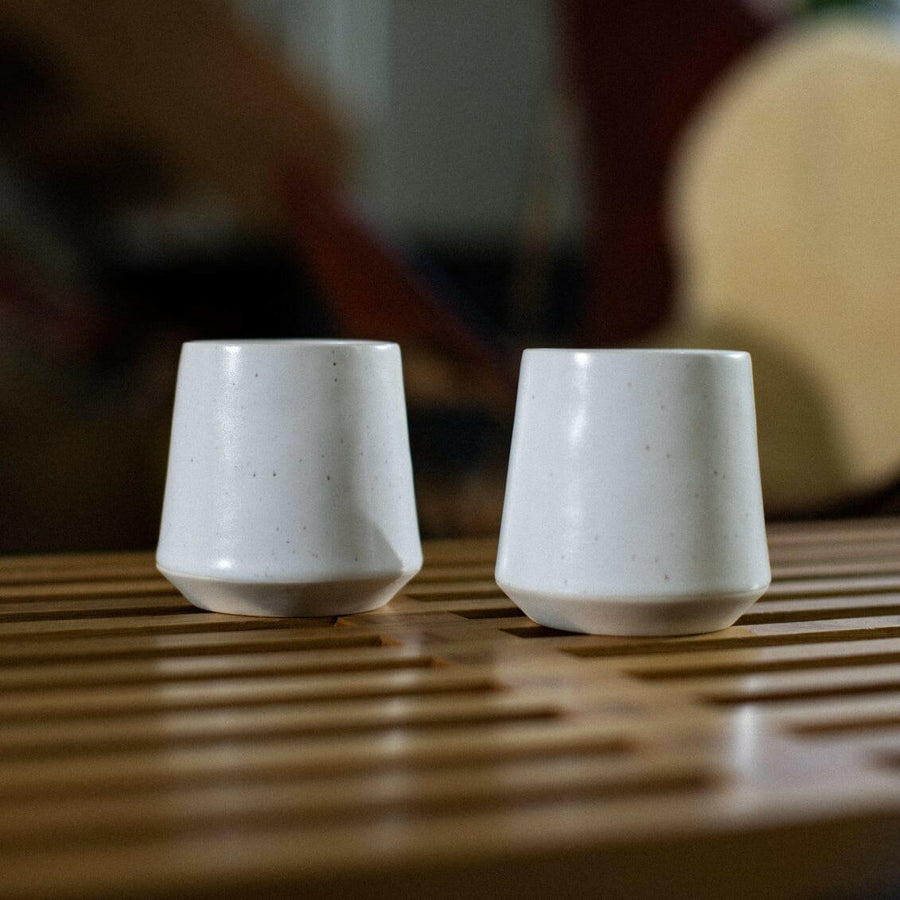 Elegant ceramic cups arranged neatly on a polished wooden table, perfect for morning coffee or tea rituals.