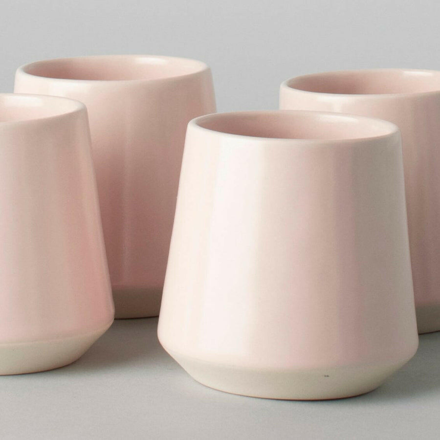 Elegant ceramic cups arranged neatly on a polished wooden table, perfect for morning coffee or tea rituals.