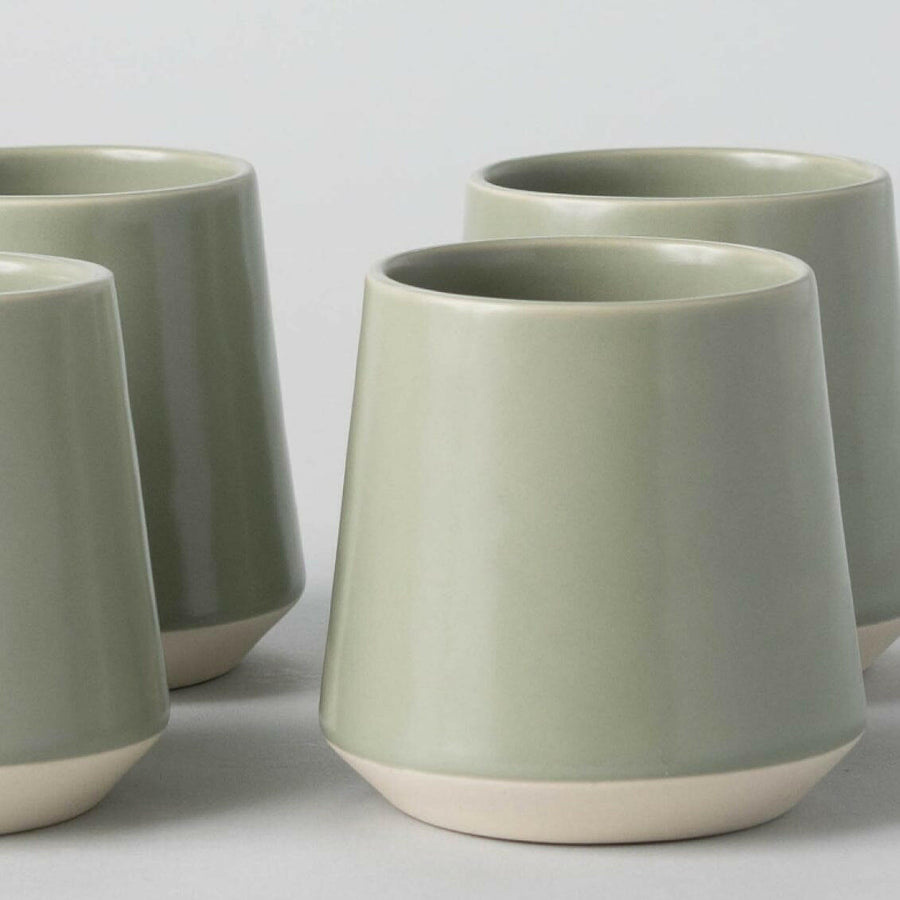 Elegant ceramic cups arranged neatly on a polished wooden table, perfect for morning coffee or tea rituals.