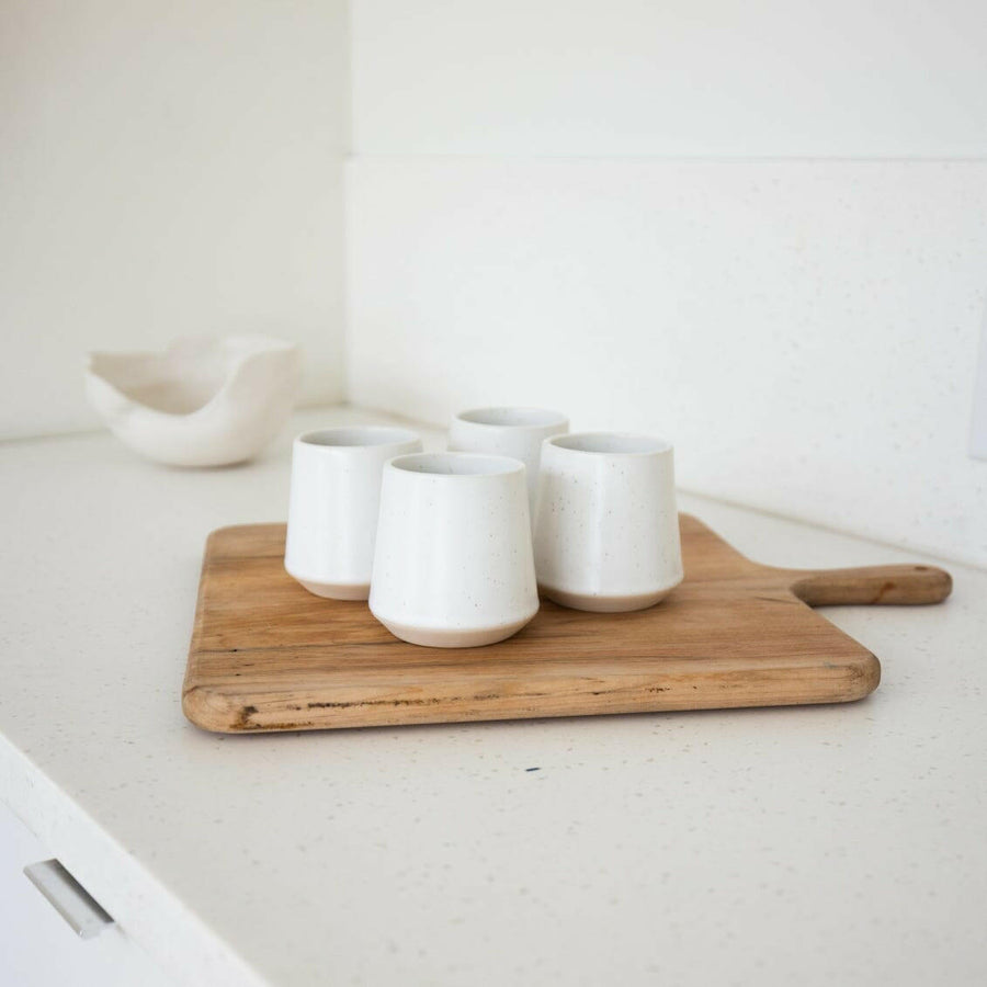 Elegant ceramic cups arranged neatly on a polished wooden table, perfect for morning coffee or tea rituals.