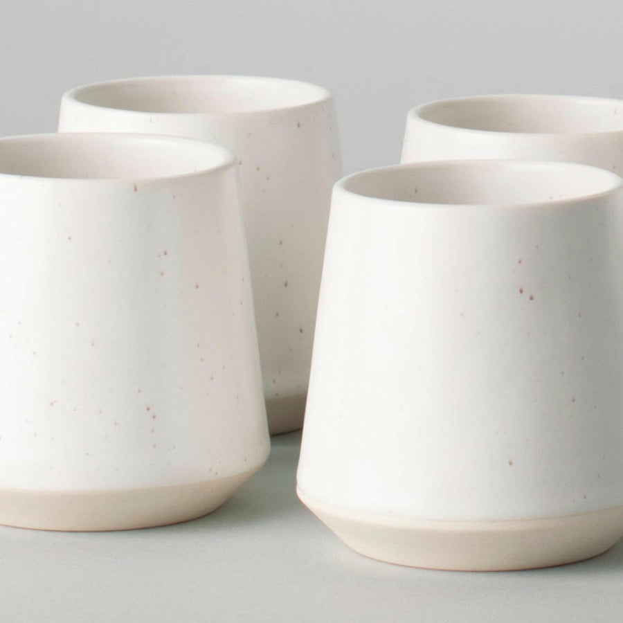 Elegant ceramic cups arranged neatly on a polished wooden table, perfect for morning coffee or tea rituals.